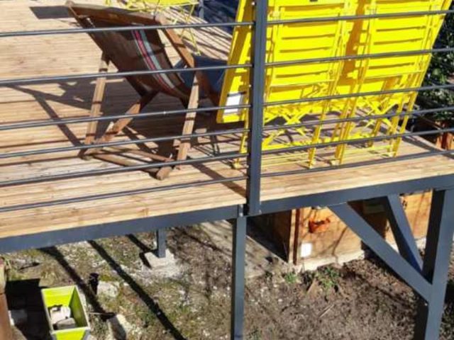 structure en alu sur pilotis d'une terrasse suspendue bois-métal avec salon de jardin